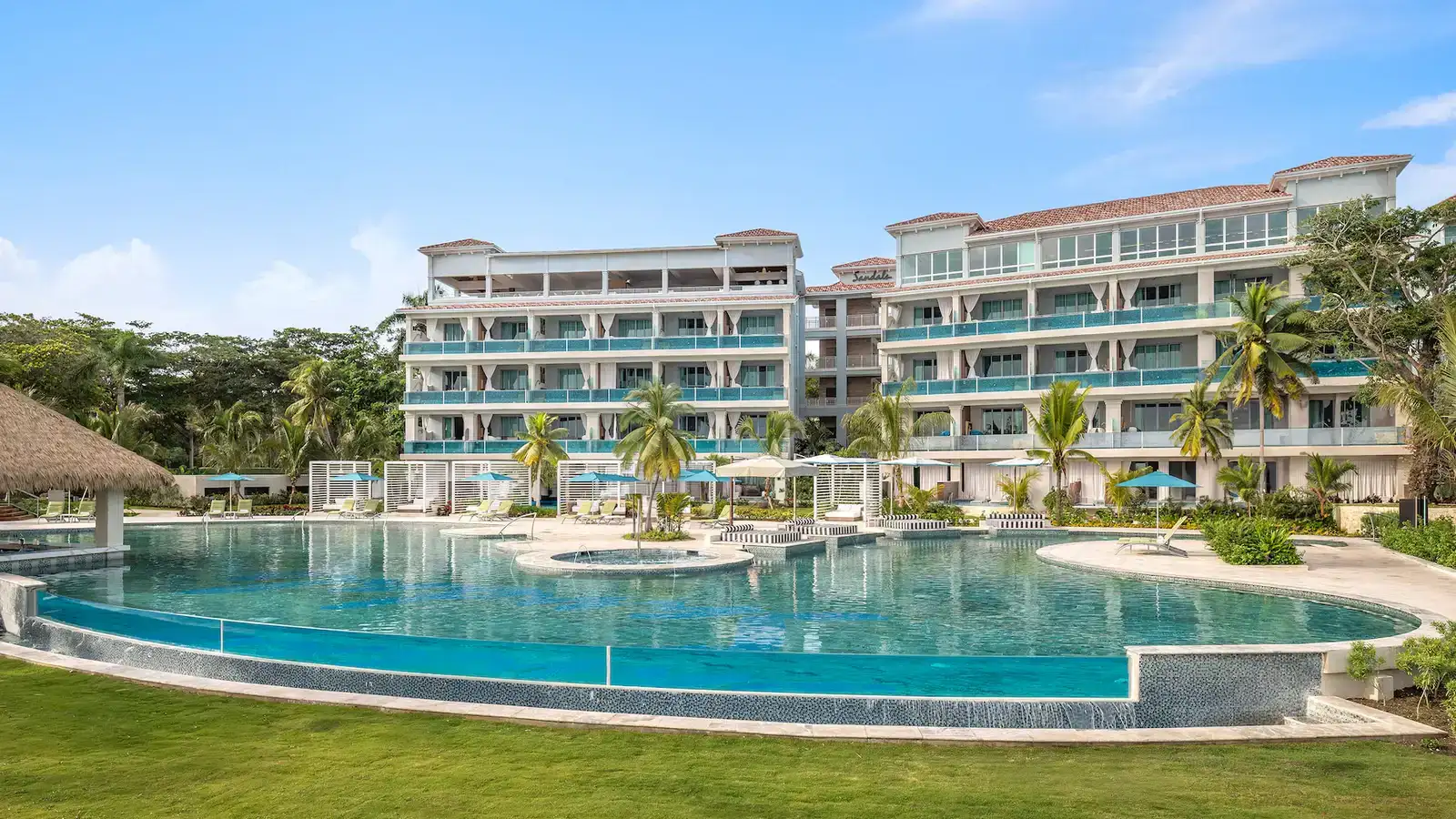 River-style winding pool at Sandals Dunn's River with couples relaxing on premium loungers