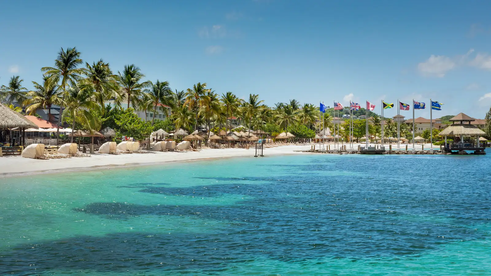 Pristine white sand beach at Sandals Grande St. Lucian with couple walking at sunset