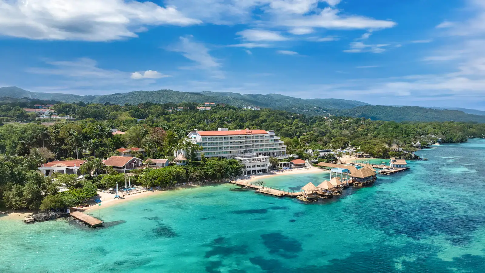 A panoramic view of Sandals Ochi, a massive, lush tropical resort in Jamaica spread across a hillside.