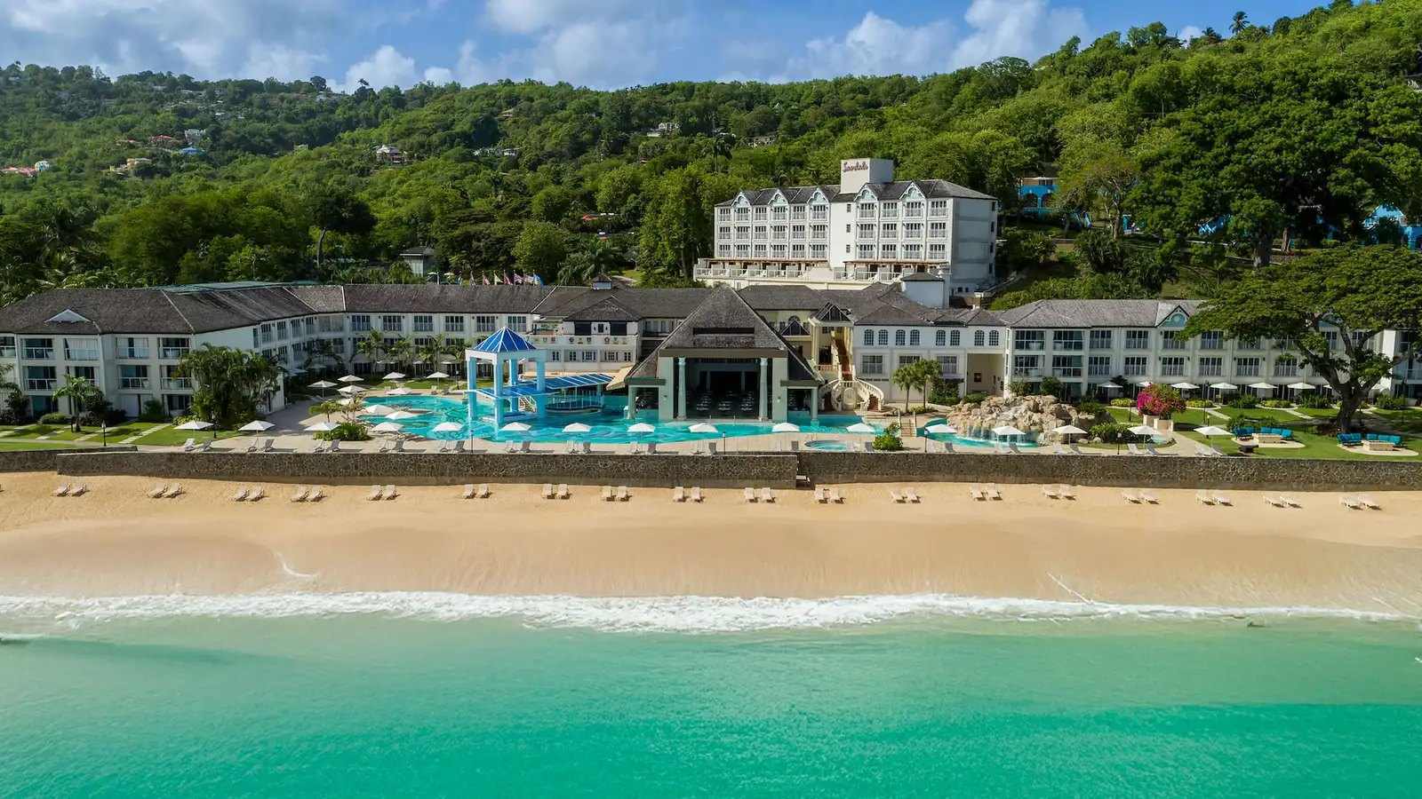 Aerial view of Sandals Regency La Toc resort built into lush hillside overlooking a crescent bay in St. Lucia